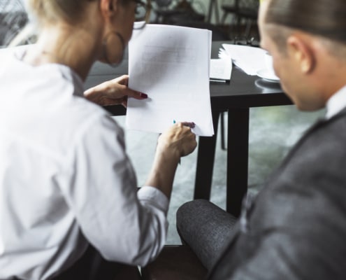 vista trasera dos empresarios examinando documento caf