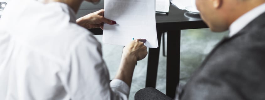 vista trasera dos empresarios examinando documento caf